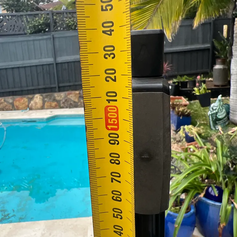 Tape measure held beside a pool gate latch to check its height
